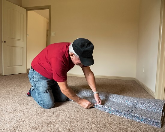 Senior Man Cutting a carept pad to lay underneath carpet