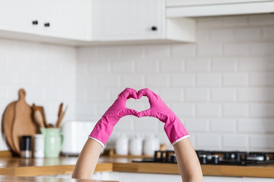 Heart made of pink protective gloves on white kitchen background.. Woman hands wearing protective gloves. Concept of clean kitchen, successful thumb up yes ok sign