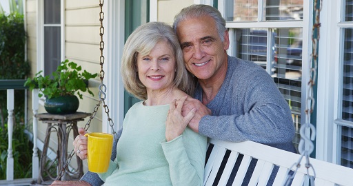 Elderly couple smiling on porch looking at camera