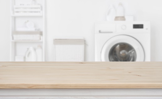 Wooden table in front of defocused washing machine and laundry